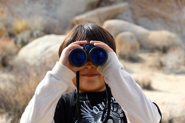 un enfant qui regarde dans notre direction avec des jumelles